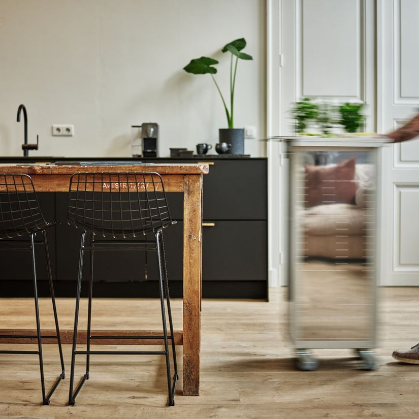 Mann triller bordbar mot kjøkkenbord med stoler